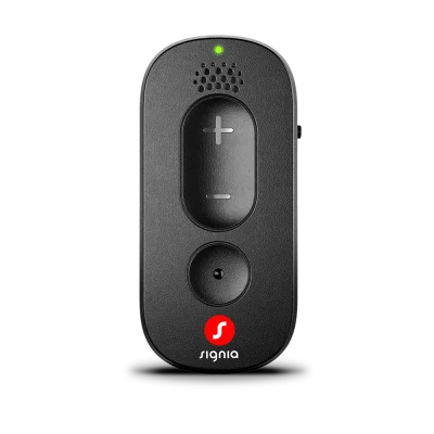 The Signia Remote Control, in black, features plus and minus buttons, a round button positioned below them, a speaker grill at the top, a small green LED light indicator, and the Signia logo at the bottom—all set against a white background.